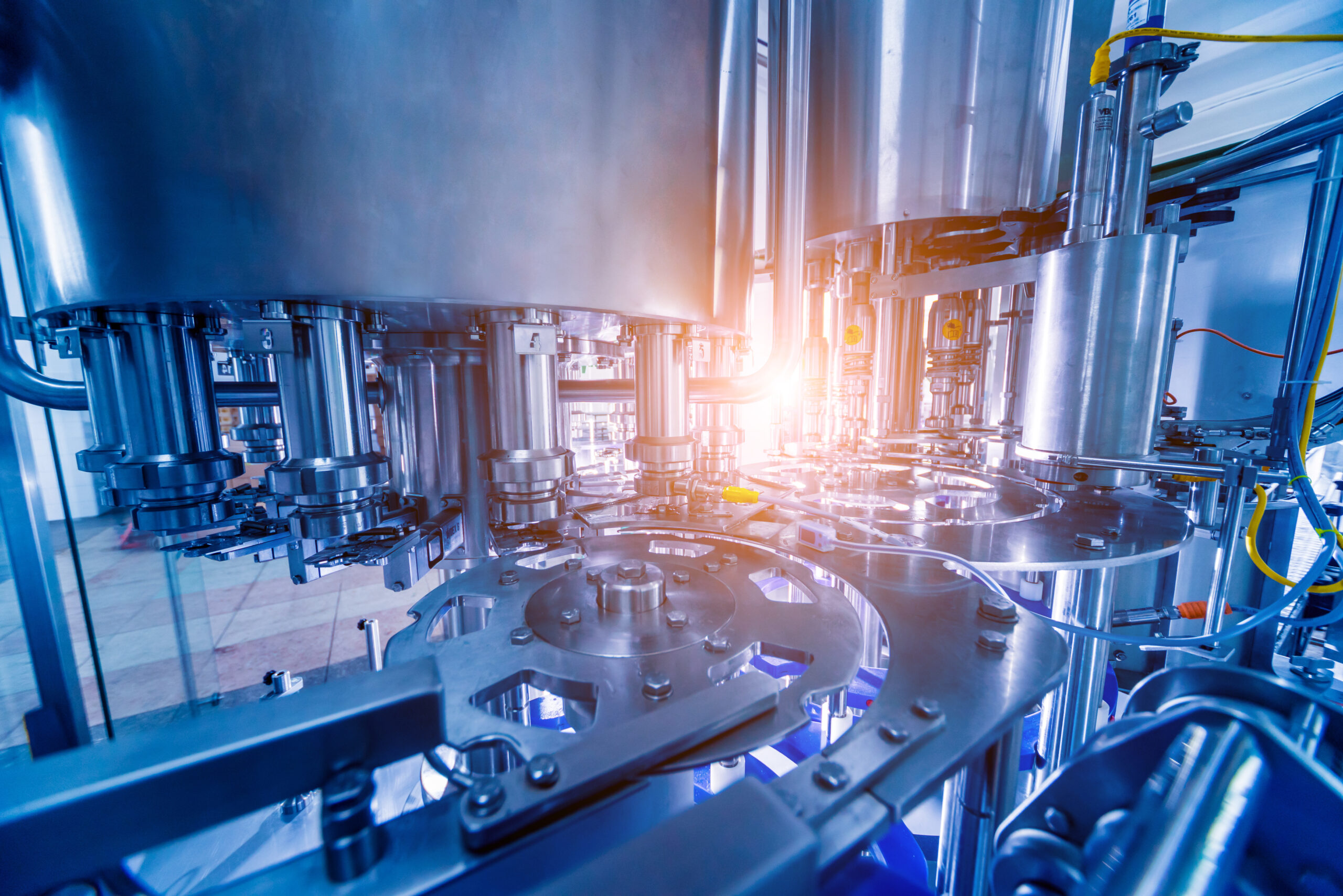 Automatic filling machine pours water into plastic PET bottles. Brewing production. Industrial background.